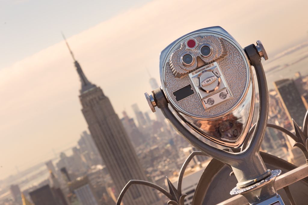 Tourist binoculars on the Top of the Rock observation deck with the Empire State Building behind at sunset, New York