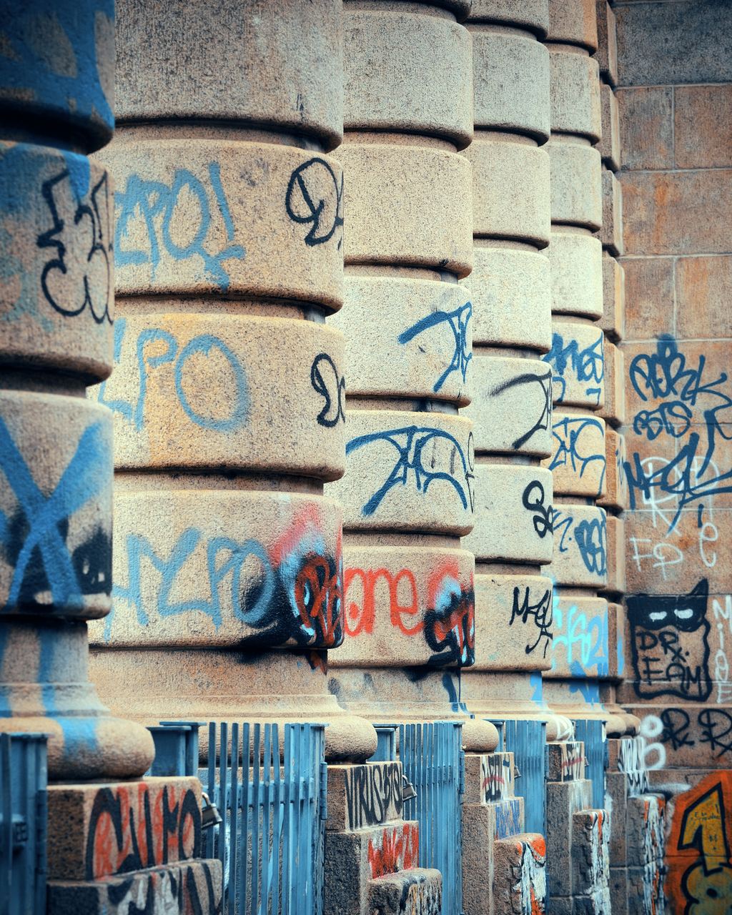 Colourful graffiti tags covering the rusticated stone piers of an old building in New York City, a glimpse of the city's street art