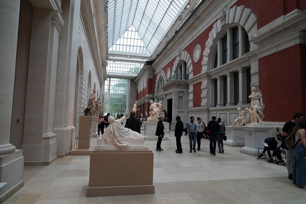 The glass-roofed Petrie European Sculpture Court at the Metropolitan Museum, with European marble sculpture and the red-brick outer wall of a 19th-century museum wing now indoors