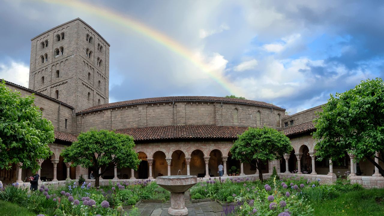 The Cuxa Cloister garden at The Met Cloisters in Fort Tryon Park, New York, with its arcades, trees and the stone tower behind