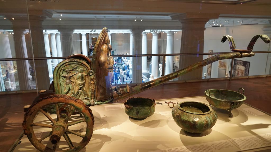 An Etruscan bronze parade chariot with embossed panels and bronze vessels in a glass case in the Greek and Roman galleries of the Metropolitan Museum of Art