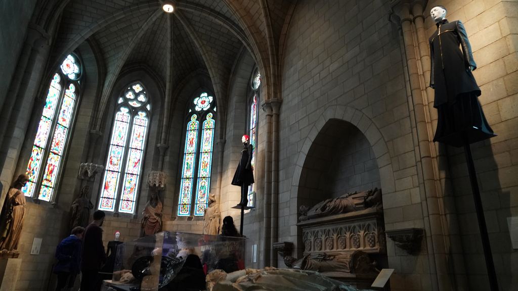 Stained-glass windows and stone tomb effigies in a Gothic chapel gallery of the Metropolitan Museum of Art