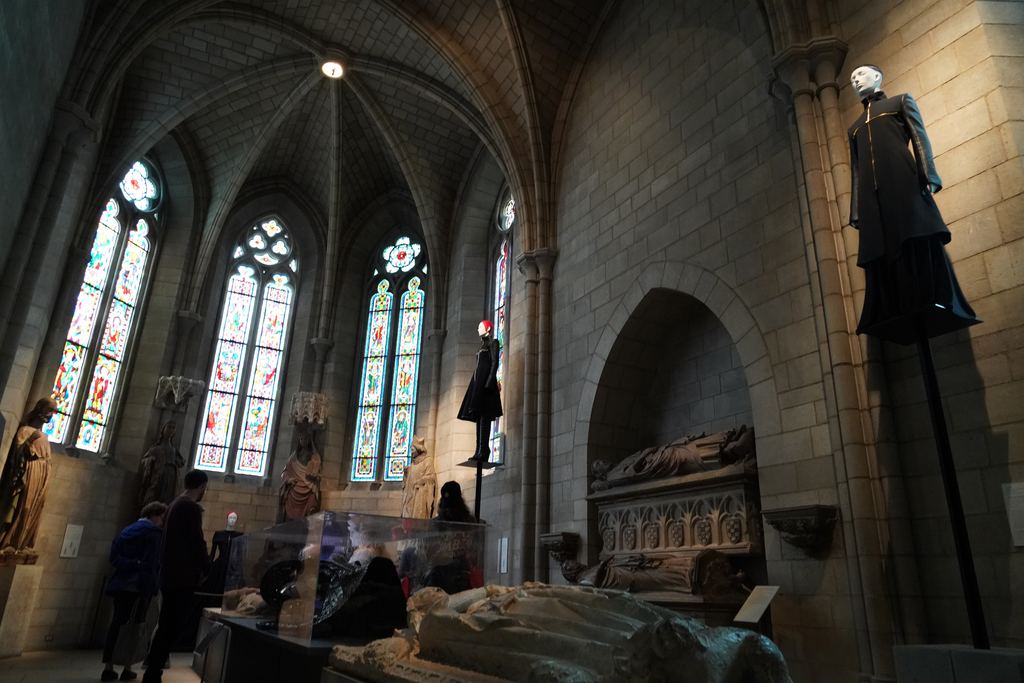 The Gothic Chapel at The Met Cloisters, with stained-glass windows, stone tomb effigies and a gown from the 2018 Heavenly Bodies exhibition