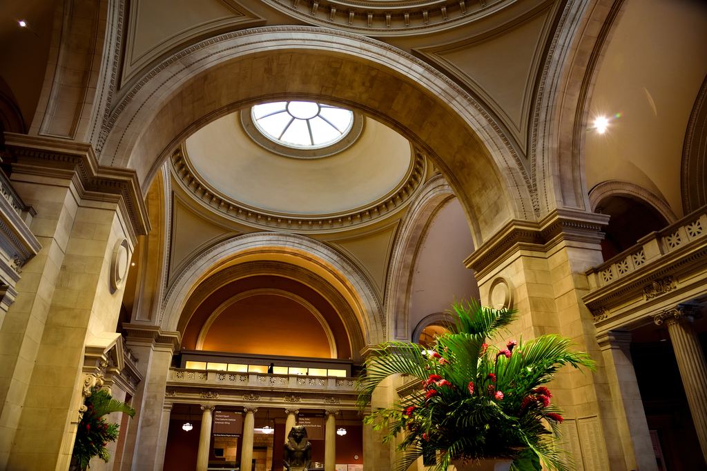 Arches, domes and skylight of the Great Hall of the Metropolitan Museum of Art on Fifth Avenue, with a large flower arrangement on a pedestal