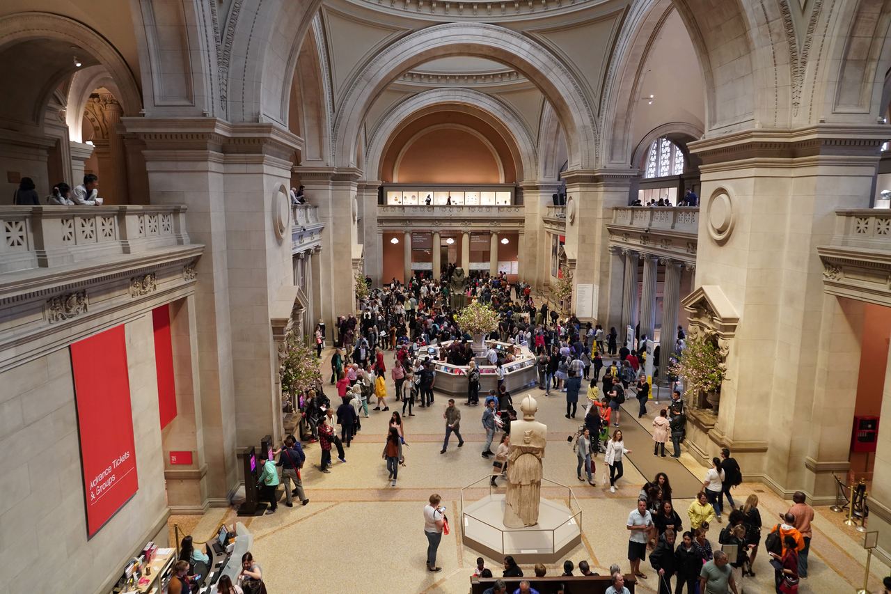 The Great Hall of the Metropolitan Museum of Art seen from the balcony, with visitors crossing the entrance floor under the domed bays