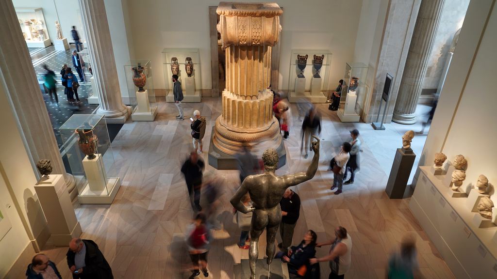 Visitors walking around a tall Ionic column and a bronze statue in a Greek and Roman gallery of the Metropolitan Museum of Art
