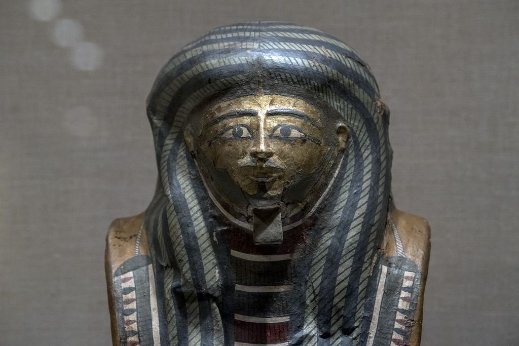 The gilded face and blue striped wig of an ancient Egyptian coffin in the Egyptian galleries of the Metropolitan Museum, New York