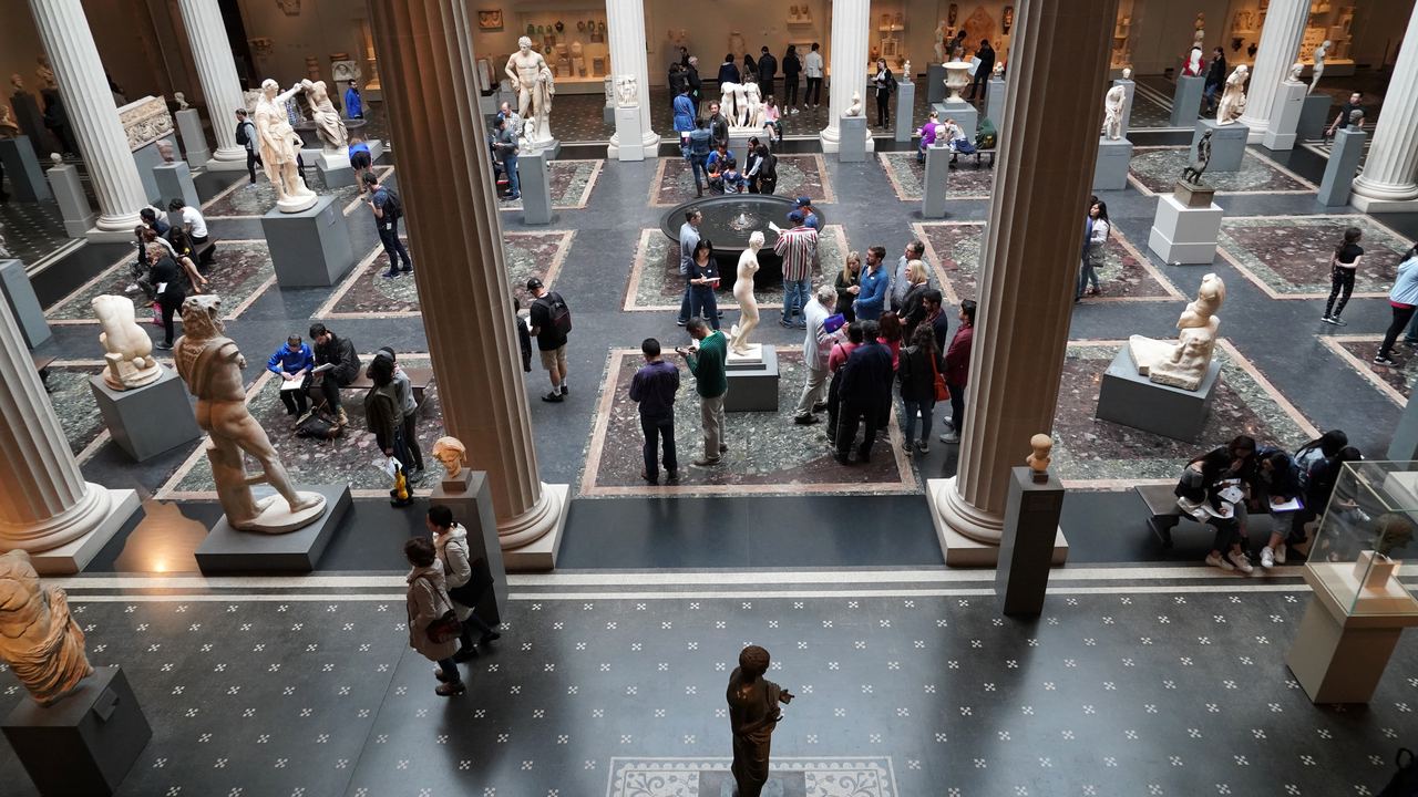 Visitors crossing the Roman sculpture court of the Metropolitan Museum of Art in New York, seen from above between the columns