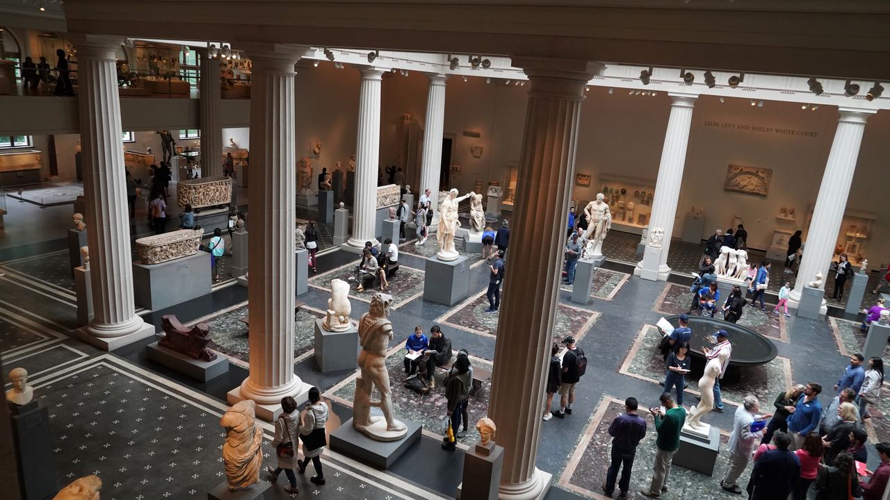 Visitors filling the Roman sculpture court of the Metropolitan Museum of Art in New York, seen from the mezzanine between the columns