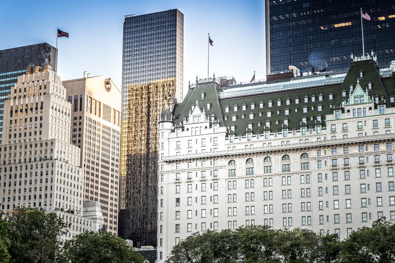 The Plaza Hotel, the 1907 French Renaissance landmark on Fifth Avenue at Central Park South, seen from the park between older and modern towers